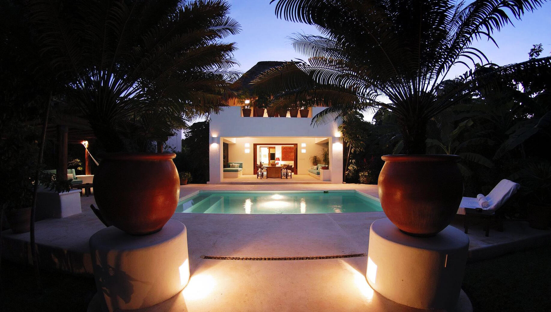 Casa con piscina entre palmeras al anochecer